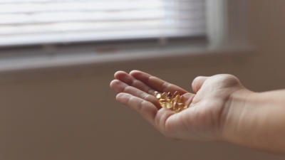 Een outstreatched hand die een handvol tabletten licht vasthoudt.